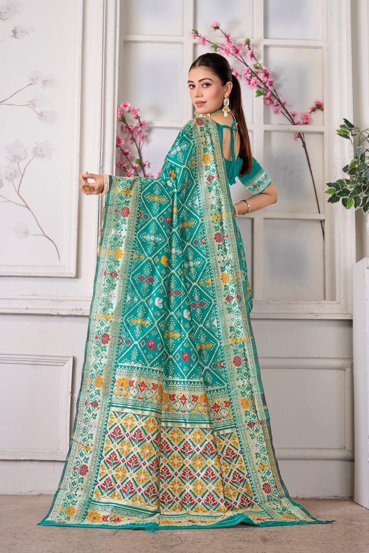 A turquoise Patola saree, pallu held open