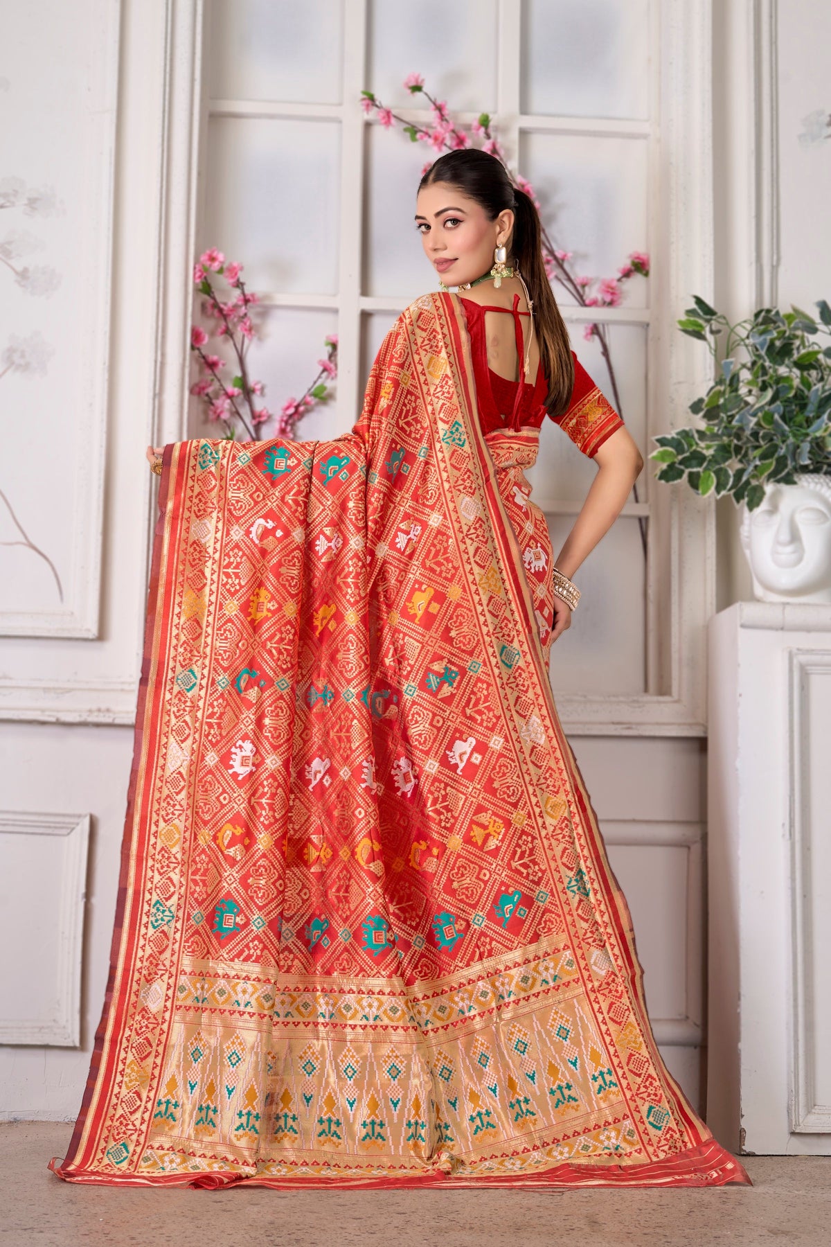 A bright red Patola saree, pallu held open