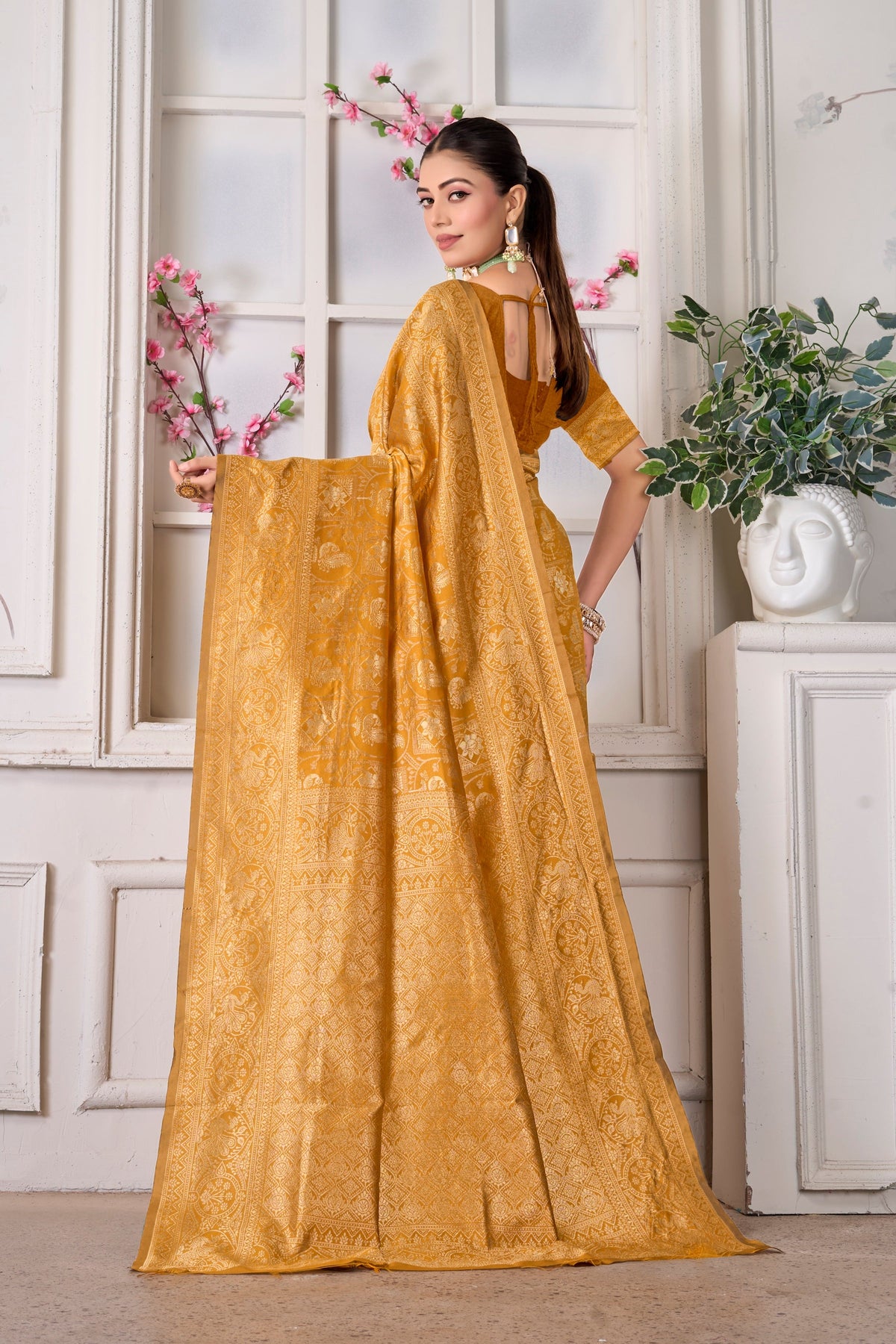 A mustard Banarasi saree, pallu held open